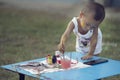 Girl with dirty hands and fingers, using paintbrush painting on paper and her Tank top