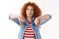 Girl disappointed bad movie. Reluctant redhead curly-haired female look away bored show thumbs down displeased express