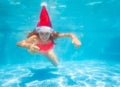 Girl dive underwater in Santa hat with thumb up Royalty Free Stock Photo