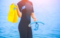 A girl diver in a wet suit holds a mask with a blue tube in her hands and a yellow fin Royalty Free Stock Photo