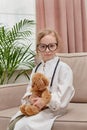 Girl in doctor clothes and glasses. The child holds in his hands his toy Royalty Free Stock Photo
