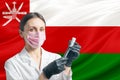 Girl doctor prepares vaccination against the background of the Oman flag. Vaccination concept Oman