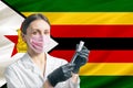 Girl doctor prepares vaccination against the background of the Zimbabwe flag. Vaccination concept Zimbabwe Royalty Free Stock Photo