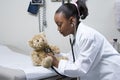 Girl doctor using stethoscope on teddy bear