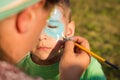 Girl does greasepaint on the child's face