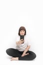 Girl does yoga and holds phone. Applications for yoga and asana practices. Portrait of woman in half lotus pose on white Royalty Free Stock Photo