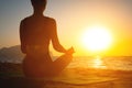 girl does yoga and meditates in lotus position on the beach. silhouette of a young woman by the sea at dawn, healthy Royalty Free Stock Photo