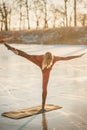 A girl does yoga in winter on the ice of the lake during the sunset Royalty Free Stock Photo