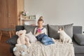 Girl and dog laying on couch in headphones, listening to music with her smarthphone. Little girl watching cartoons on her phone.