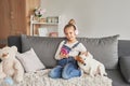 Girl and dog laying on couch in headphones, listening to music with her smarthphone. Little girl watching cartoons on her phone.