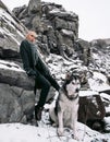 Girl with dog Malamute among rocks in winter. Royalty Free Stock Photo