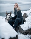 Girl with dog Malamute among rocks in winter. Royalty Free Stock Photo