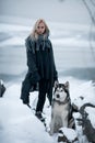 Girl with dog Malamute among rocks in winter.