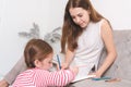 Girl doing homework in the living room and mom helping her child Royalty Free Stock Photo