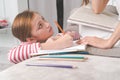 Girl doing homework in the living room and mom helping her child Royalty Free Stock Photo