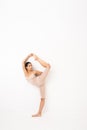 Girl doing stretching in the studio on a white background. A beautiful gymnast with a flexible body and athletic uniform