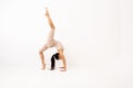 Girl doing stretching in the studio on a white background. A beautiful gymnast with a flexible body and athletic uniform