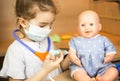 A girl with a doll plays doctor, makes a syringe inoculation in the hand. Vaccination, vaccination calendar, vaccine, profession