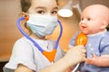 A girl with a doll plays doctor, a nurse listens to the baby through a stethoscope. Pediatrics, vaccination calendar, profession Royalty Free Stock Photo