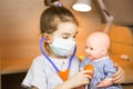 A girl with a doll plays doctor, a nurse listens to the baby through a stethoscope. Pediatrics, vaccination calendar, profession Royalty Free Stock Photo