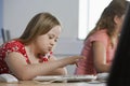 Girl (10-12) with Down syndrome using computer in computer lab children in background