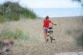 Girl drags a bicycle on the sand at the seaside