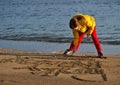 Girl drawing in beach sand Royalty Free Stock Photo