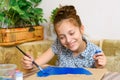 A girl drawing blue gouache cardboard, artistic creation at home, makes creative artwork