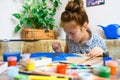 A girl drawing blue gouache cardboard, artistic creation at home, makes creative artwork