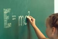 Girl drawing on chalkboard formula e=mc2. Education and school concept Royalty Free Stock Photo