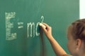 Girl drawing on chalkboard formula e mc2. Education and school concept Royalty Free Stock Photo