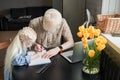 Girl drawing hand made picture with her father while he sitting at his workplace