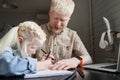 Girl drawing hand made picture with her father while he sitting at his workplace