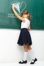 Girl drawing heart with chalk on blackboard