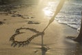 Girl drawing a heart on the sand at sunset in a summer love concept Royalty Free Stock Photo