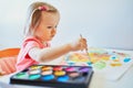 Girl drawing rainbow with colorful aquarelle paints Royalty Free Stock Photo
