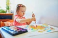 Girl drawing rainbow with colorful aquarelle paints Royalty Free Stock Photo