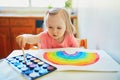 Girl drawing rainbow with colorful aquarelle paints Royalty Free Stock Photo