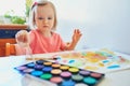 Girl drawing rainbow with colorful aquarelle paints Royalty Free Stock Photo