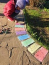 the girl draws bright colored crayons on a stone path in the country outside the city