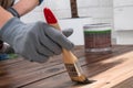 The girl draws with brown paint. Girl with a brush in her hand paints wooden boards. Royalty Free Stock Photo