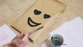 The girl draws with a brush on paper bags various emotions. The concept of emotions in smileys