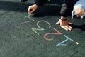 The girl draws with chalk numbers on the Playground