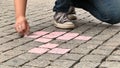 The girl draws with chalk on the pavement