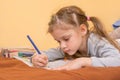 Girl draws a hard lying on his stomach with a pencil on paper Royalty Free Stock Photo
