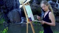 Girl draws on plein air mountain waterfall and lake background