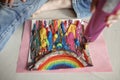 Girl draws rainbow with melted crayon pencils, she using blow dryer and wax stars to melt, art idea