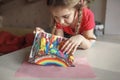 Girl draws rainbow with melted crayon pencils, she using blow dryer and wax stars to melt, art idea Royalty Free Stock Photo