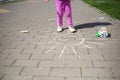 Girl draws sun with chalk on sidewalk. kids walk outdoor. summer activity