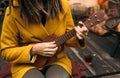 Girl with dreadlocks closeup playing an acoustic instrument ukulele in autumn on the terrace